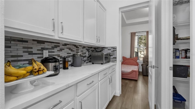 kitchen featuring light stone counters, white cabinetry, light hardwood / wood-style flooring, and tasteful backsplash