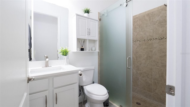 bathroom with vanity, toilet, and a shower with door