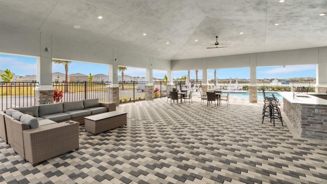 view of patio / terrace with outdoor lounge area, ceiling fan, a community pool, and exterior bar