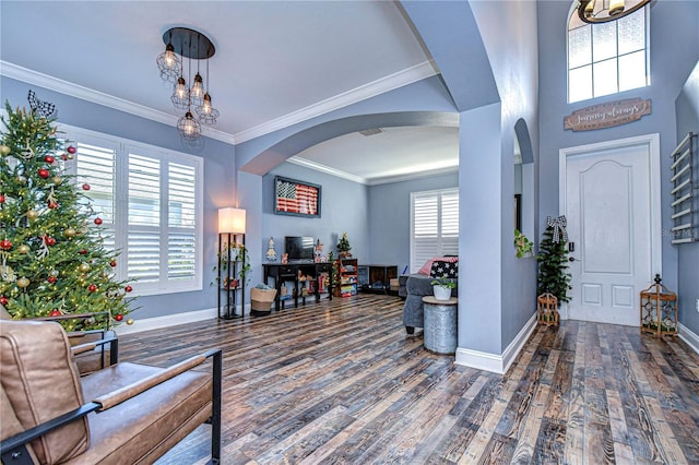 foyer entrance with baseboards, crown molding, arched walkways, and wood finished floors