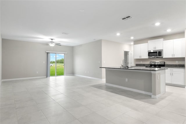 kitchen featuring stainless steel appliances, a kitchen island with sink, ceiling fan, sink, and white cabinetry