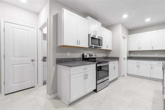 kitchen with appliances with stainless steel finishes, white cabinetry, and dark stone countertops