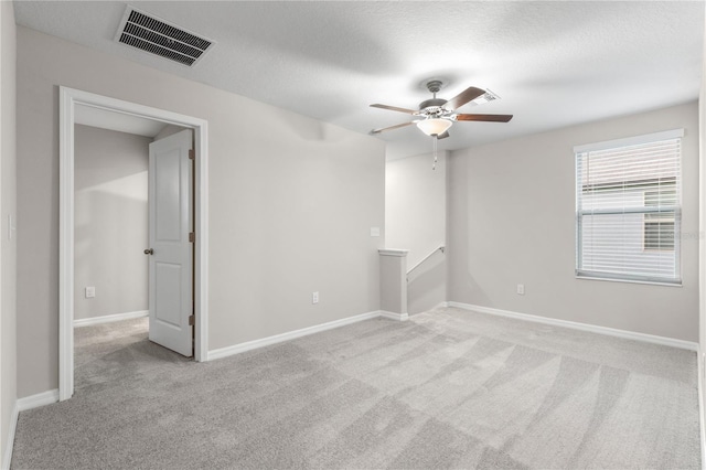 spare room with light carpet, a textured ceiling, and ceiling fan