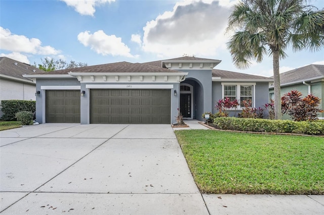 view of front of home featuring a garage, concrete driveway, a front lawn, and stucco siding