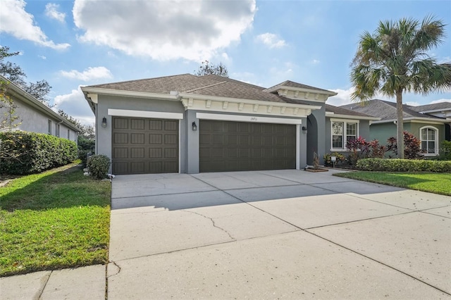 view of front of house with an attached garage, a shingled roof, driveway, stucco siding, and a front yard