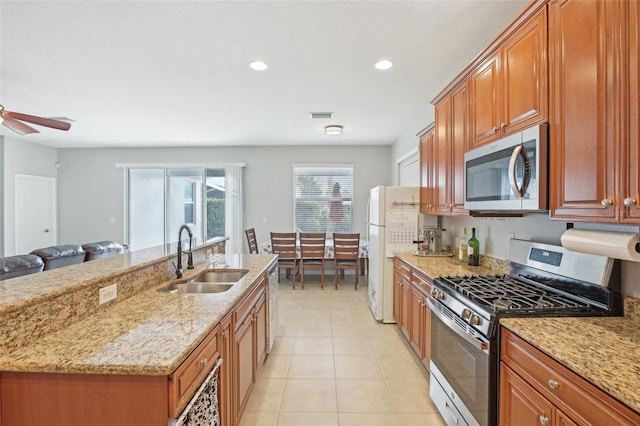 kitchen featuring ceiling fan, sink, light stone countertops, and stainless steel appliances