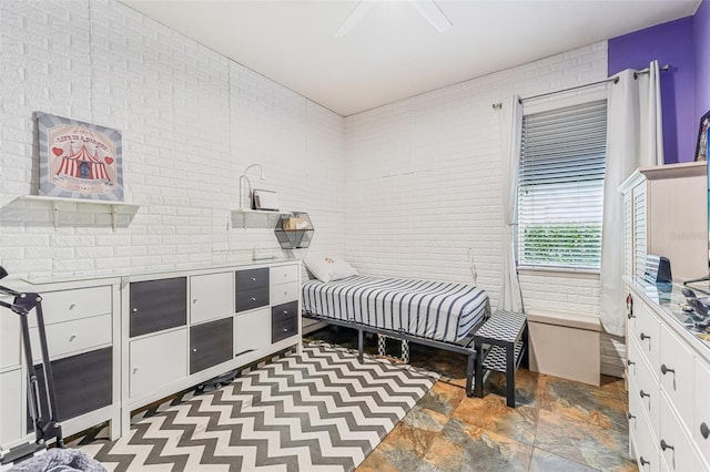 bedroom featuring ceiling fan and brick wall