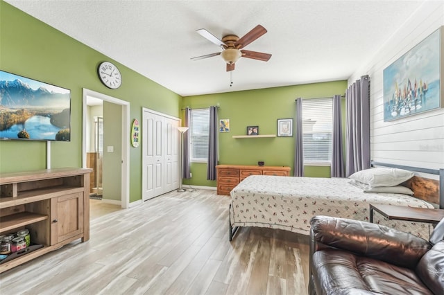 bedroom with ceiling fan, a closet, a textured ceiling, and light wood-type flooring