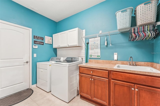 clothes washing area with washer and clothes dryer, sink, light tile patterned flooring, and cabinets