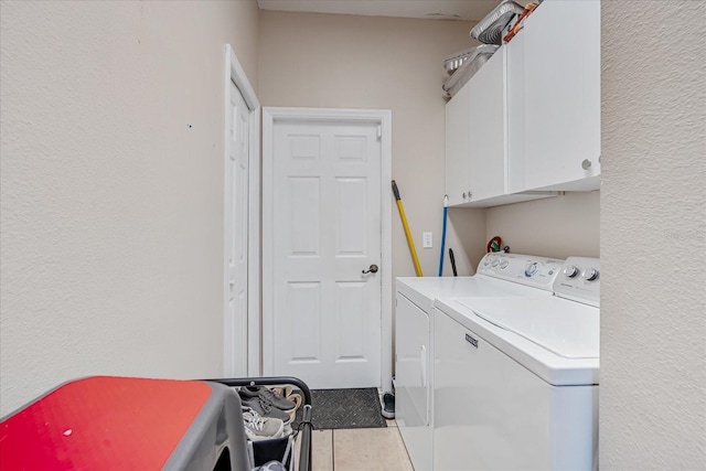 laundry room with cabinets, light tile patterned floors, and washing machine and clothes dryer