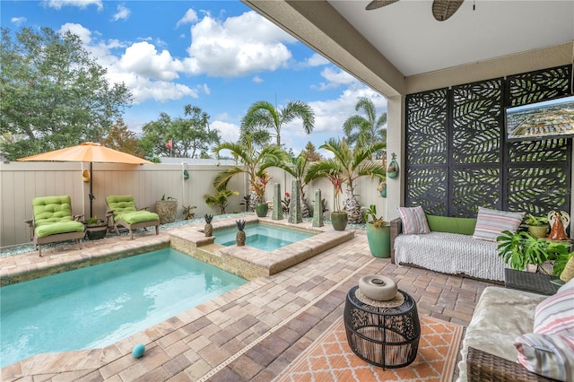 view of swimming pool featuring a patio, glass enclosure, a fenced backyard, ceiling fan, and an in ground hot tub