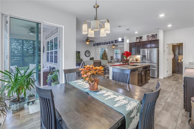 dining space with ceiling fan with notable chandelier and sink