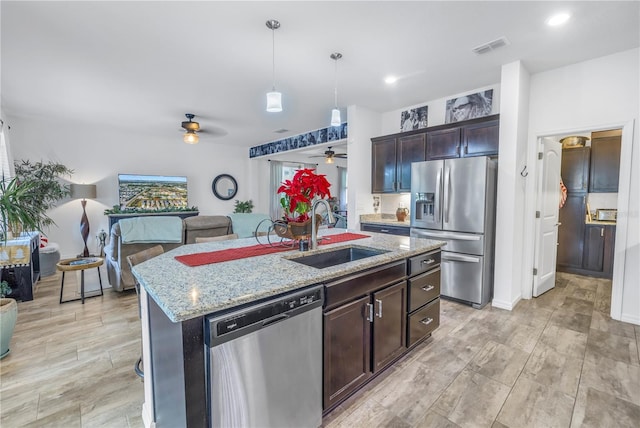 kitchen featuring sink, decorative light fixtures, a kitchen island with sink, dark brown cabinets, and appliances with stainless steel finishes