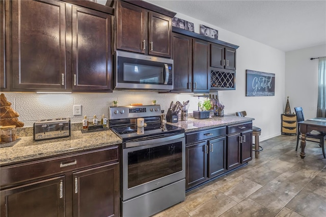 kitchen featuring dark brown cabinets, stainless steel appliances, and light stone counters