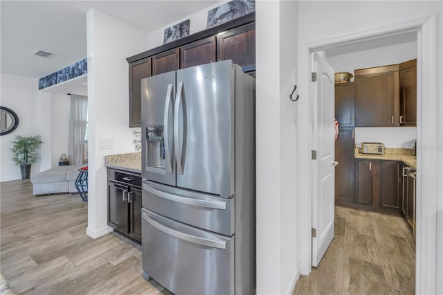 kitchen with light hardwood / wood-style floors, light stone counters, dark brown cabinetry, and stainless steel refrigerator with ice dispenser