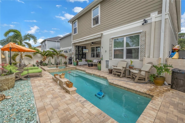 rear view of property with a swimming pool with hot tub and a patio area