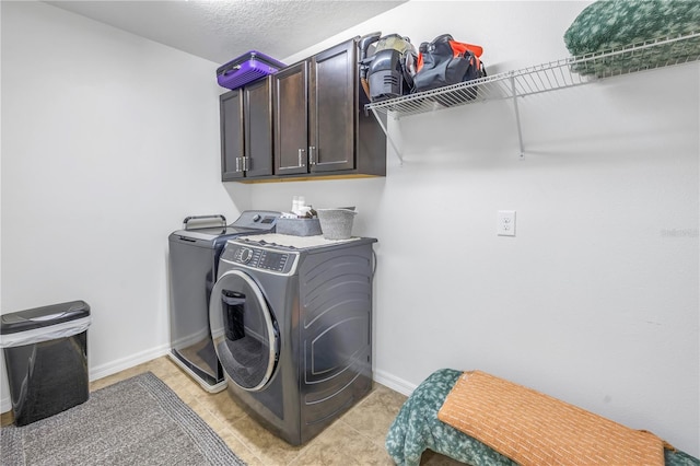 clothes washing area featuring washer and dryer, cabinets, light tile patterned floors, and a textured ceiling