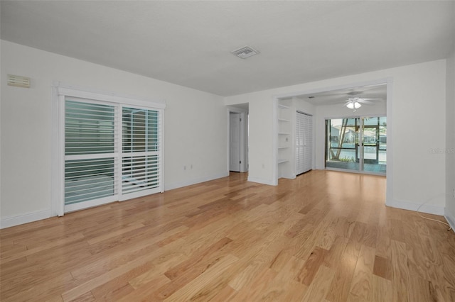 unfurnished room featuring built in shelves, ceiling fan, and light hardwood / wood-style flooring