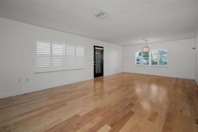 unfurnished room with an inviting chandelier and light hardwood / wood-style floors