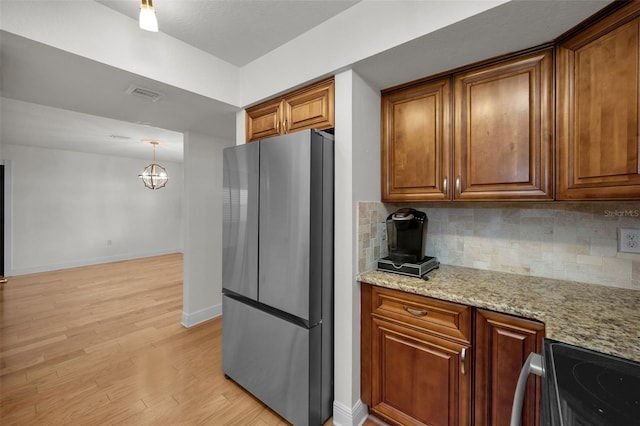 kitchen with light stone counters, backsplash, stainless steel appliances, and light hardwood / wood-style floors