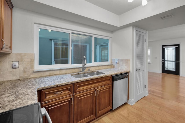 kitchen with sink, tasteful backsplash, light wood-type flooring, appliances with stainless steel finishes, and light stone countertops