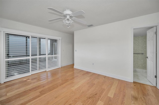 unfurnished bedroom featuring ceiling fan, ensuite bathroom, a textured ceiling, and light wood-type flooring