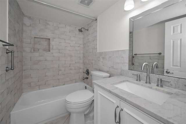 full bathroom with toilet, tile walls, a textured ceiling, vanity, and tiled shower / bath combo