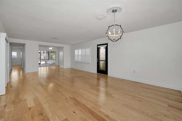 unfurnished living room featuring ceiling fan with notable chandelier and light wood-type flooring