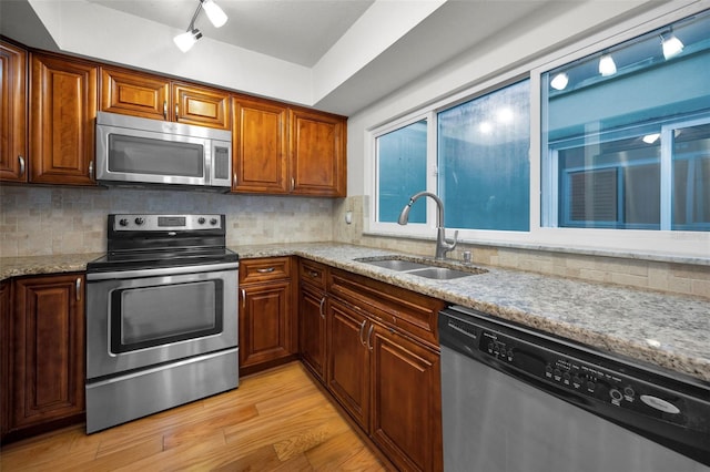 kitchen featuring stainless steel appliances, sink, decorative backsplash, and light hardwood / wood-style flooring