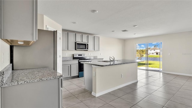 kitchen with light stone countertops, sink, light tile patterned flooring, and stainless steel appliances