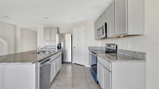 kitchen featuring sink, gray cabinets, a center island with sink, light tile patterned floors, and appliances with stainless steel finishes