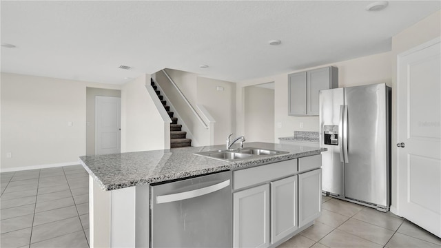 kitchen with a kitchen island with sink, sink, light tile patterned floors, and stainless steel appliances