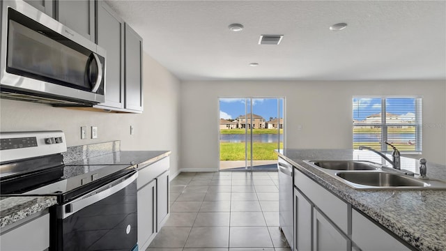 kitchen with gray cabinetry, light tile patterned floors, sink, and appliances with stainless steel finishes