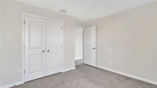 unfurnished bedroom featuring light carpet and a closet