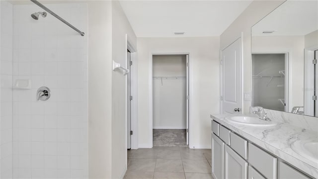 bathroom with a tile shower, vanity, and tile patterned floors