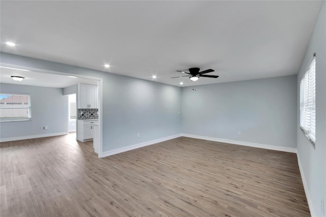 empty room with plenty of natural light, light hardwood / wood-style floors, and ceiling fan