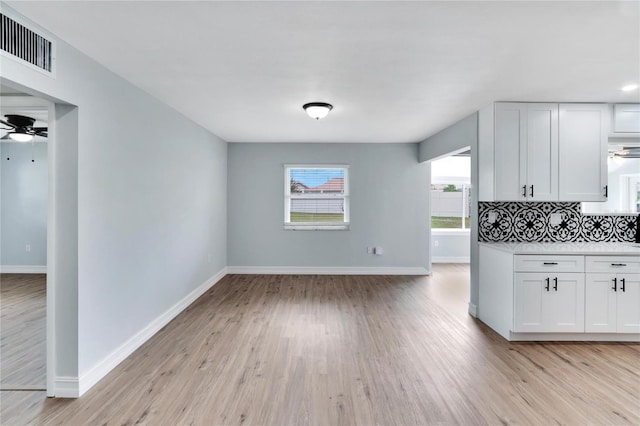 kitchen featuring backsplash, light hardwood / wood-style floors, and white cabinetry