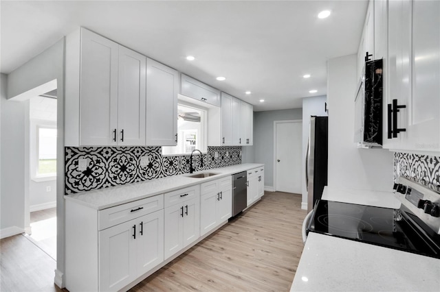 kitchen featuring sink, stainless steel appliances, light hardwood / wood-style flooring, backsplash, and white cabinets