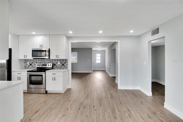 1201 Harkness Way, Sun City Center, FL 33573 - kitchen featuring stainless steel appliances, light countertops, white cabinets, decorative backsplash, and light wood-type flooring