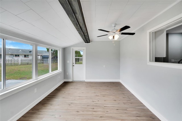 unfurnished sunroom with ceiling fan, plenty of natural light, and lofted ceiling with beams