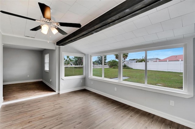 empty room featuring plenty of natural light, lofted ceiling with beams, wood-type flooring, and ceiling fan