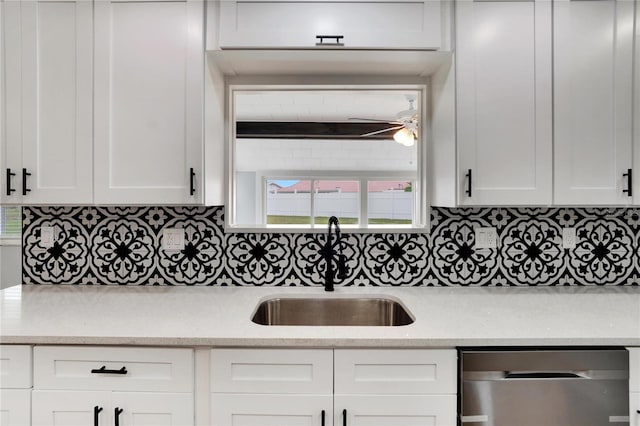 kitchen with decorative backsplash, white cabinetry, sink, and stainless steel dishwasher