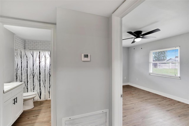 interior space featuring hardwood / wood-style floors, vanity, a shower with curtain, ceiling fan, and toilet