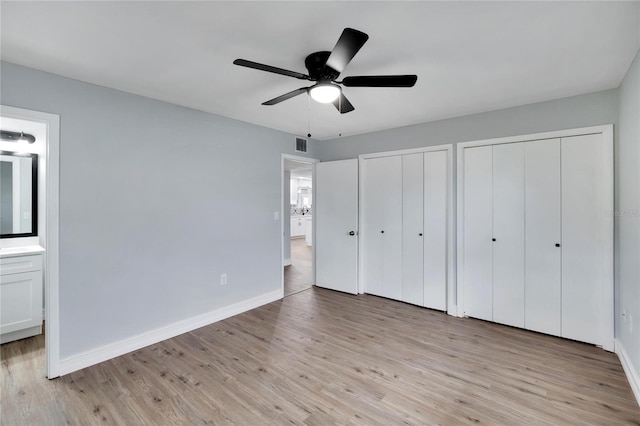 unfurnished bedroom with multiple closets, ensuite bathroom, light hardwood / wood-style flooring, and ceiling fan