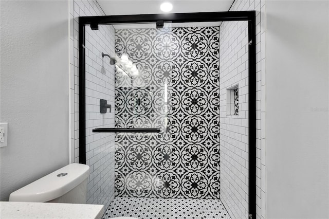 bathroom featuring toilet and a shower with shower door