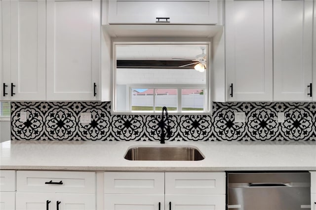 kitchen featuring a sink, backsplash, white cabinetry, light stone countertops, and dishwasher