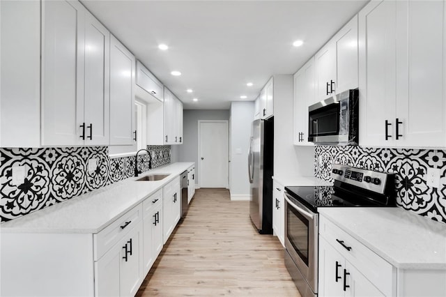 kitchen featuring recessed lighting, stainless steel appliances, a sink, light wood-type flooring, and decorative backsplash