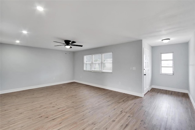 spare room featuring a ceiling fan, baseboards, a healthy amount of sunlight, and wood finished floors