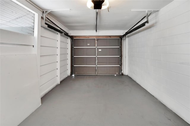 garage featuring a garage door opener and concrete block wall