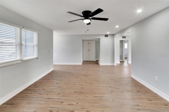 empty room with baseboards, a ceiling fan, visible vents, and light wood-type flooring